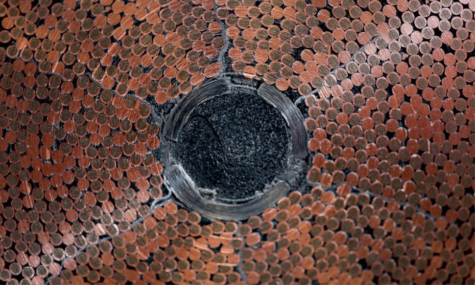 A close-up view of conductor shows the density of compacted strand around a helium cooling channel.