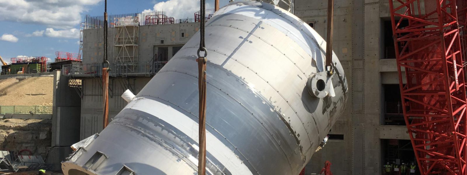 A 61,000 gallon drain tank, part of the US-provided tokamak cooling water system, is lifted into the tokamak complex for installation in the basement.