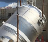 A 61,000 gallon drain tank, part of the US-provided tokamak cooling water system, is lifted into the tokamak complex for installation in the basement.